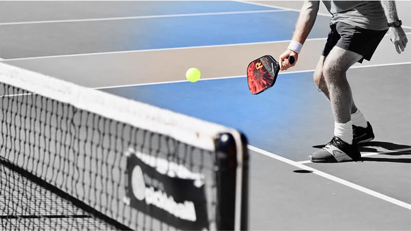 A man playing Pickleball on a court with a paddle.